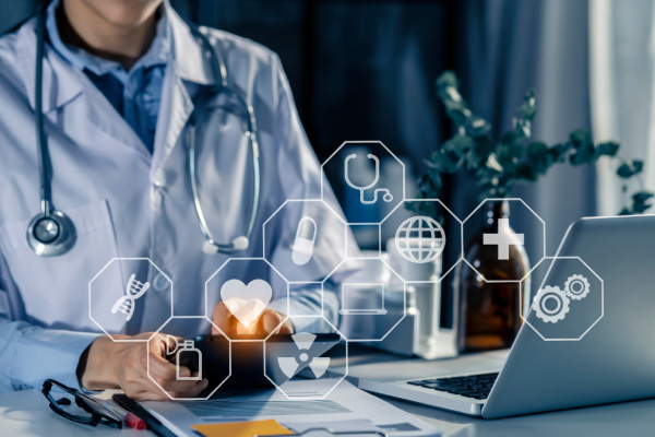 A female doctor sitting in her consultation room using a tab meanwhile a laptop, writing pad, spectacles and a pen is kept near it along with virtual images related to healthcare and medicine.