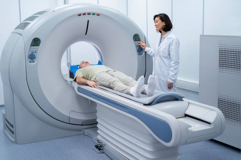 A female radiologist positioning a male patient in the CT scanner.