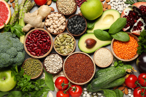 Different types of vegetables,fruits and seeds kept in bowls arranged on a grey table.