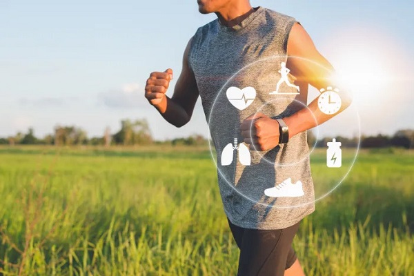 A closeup image of a man with a a smart watch jogging in a greenery filled farm and fitness related icons shown as virtual images around the watch.