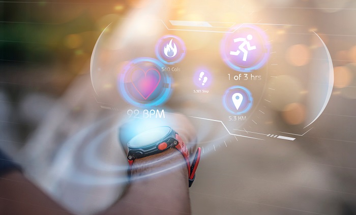 Image of a persons hand with a smart watch and a bubble above it featuring fitness icons related to futuristic smart watch technology.