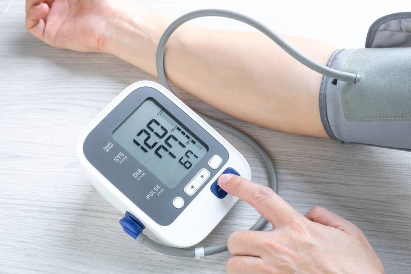 A person is measuring their blood pressure and heart rate with a digital monitor.