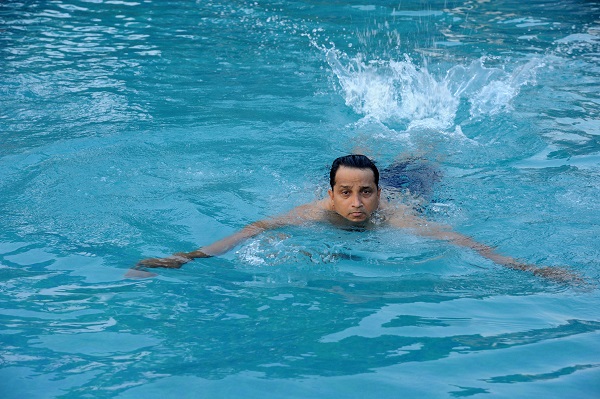 Image of a man practicing butterfly stroke swimming in a pool.