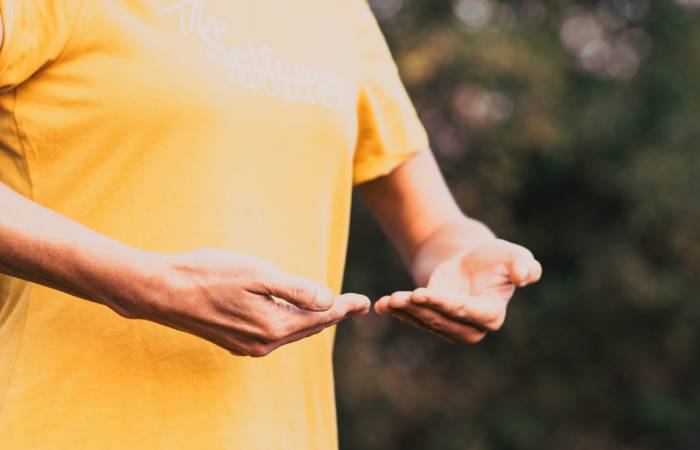 A woman doing qi gong/ breathing exercise standing outdoors.