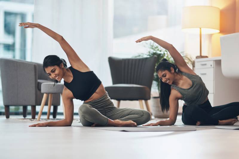 Two young women sitting on the floor doing yoga/exercise in a family lounge.