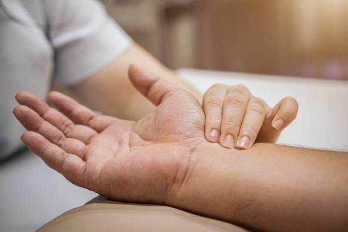 A medical expert is checking a person's pulse by hand.