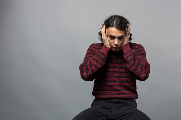 A young boy crouching, covering his ears, symbolizing fear from health risk test results.