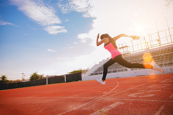 A woman sprinting on a track, emphasizing its benefits for muscle growth and the Mesomorph physique.