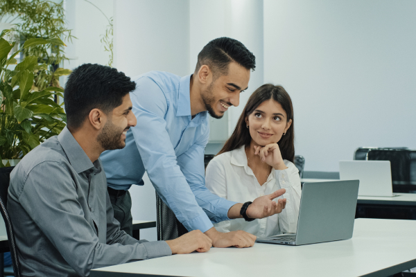 A team of friendly, creative colleagues using a computer to discuss, fostering a supportive workplace for mental health.