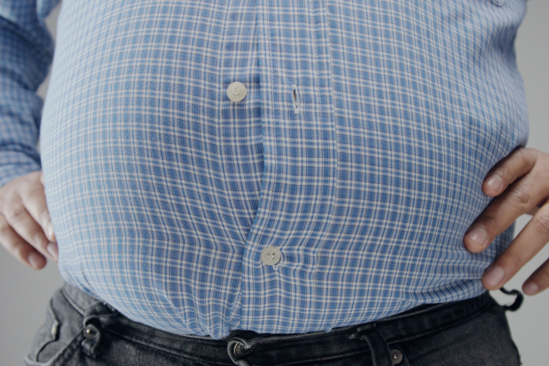 Close-up of a person with hands on hips in a checkered shirt, representing metabolic rate and body measurements.