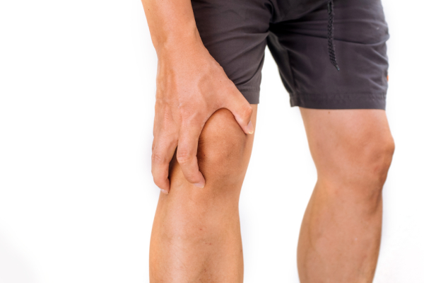 Close-up of a man's hand on his knee, showing discomfort due to knee inflammation from calcium deficiency.