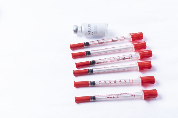 Insulin injection and syringes symbolize Type 1 diabetes and the need for insulin before testing.
